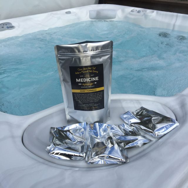 A pouch of Medicine Springs Joint Formula mineral therapy product sitting on the edge of a hot tub.