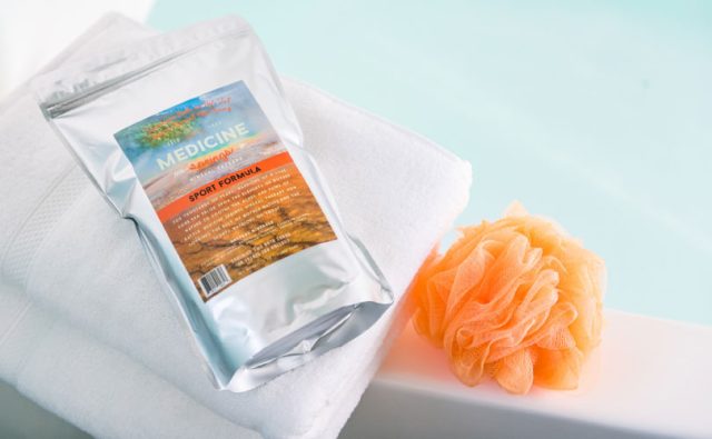 A pouch of Medicine Springs Sport Formula mineral therapy product next to a loofah sponge pouf